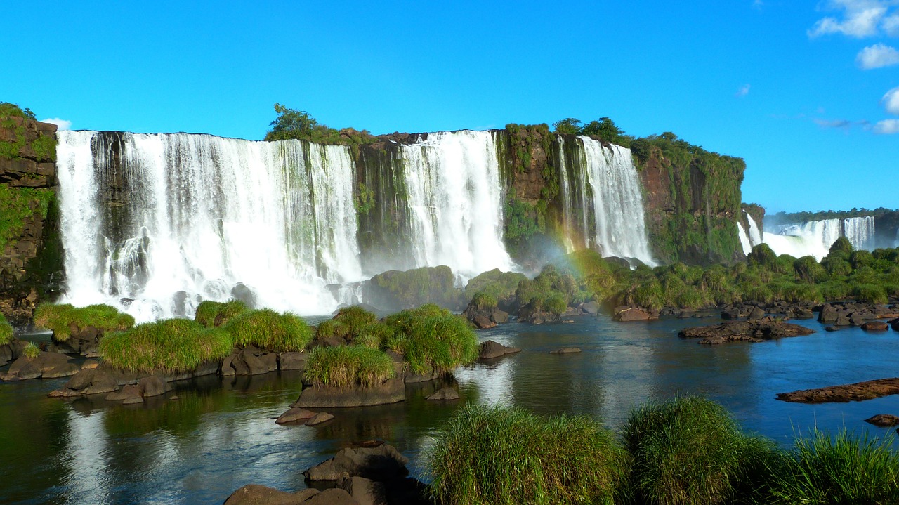 Big and wide Iguazu Falls with a small rainbow