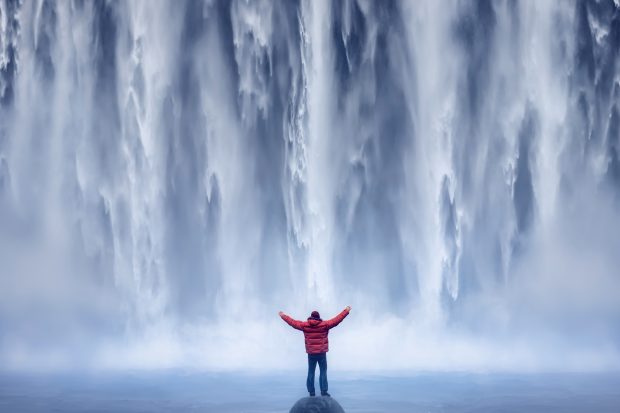 person in front of huge waterfall