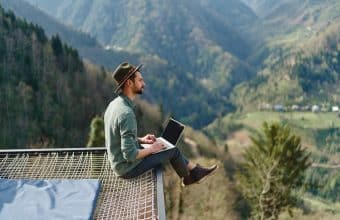 Traveller sitting on edge of nature overlooking mountains